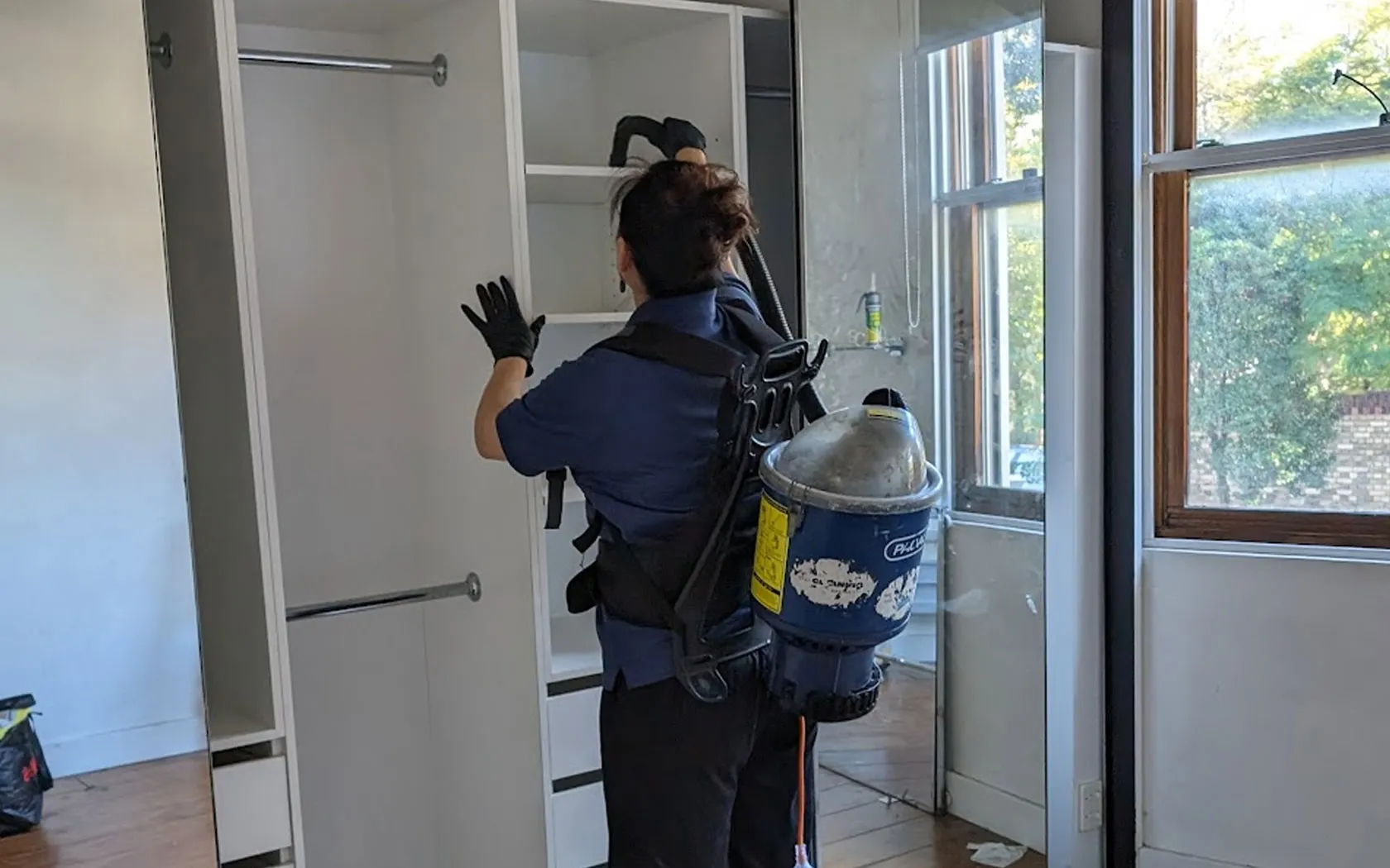 Professional cleaner detailing cupboards and wardrobes in an empty rental